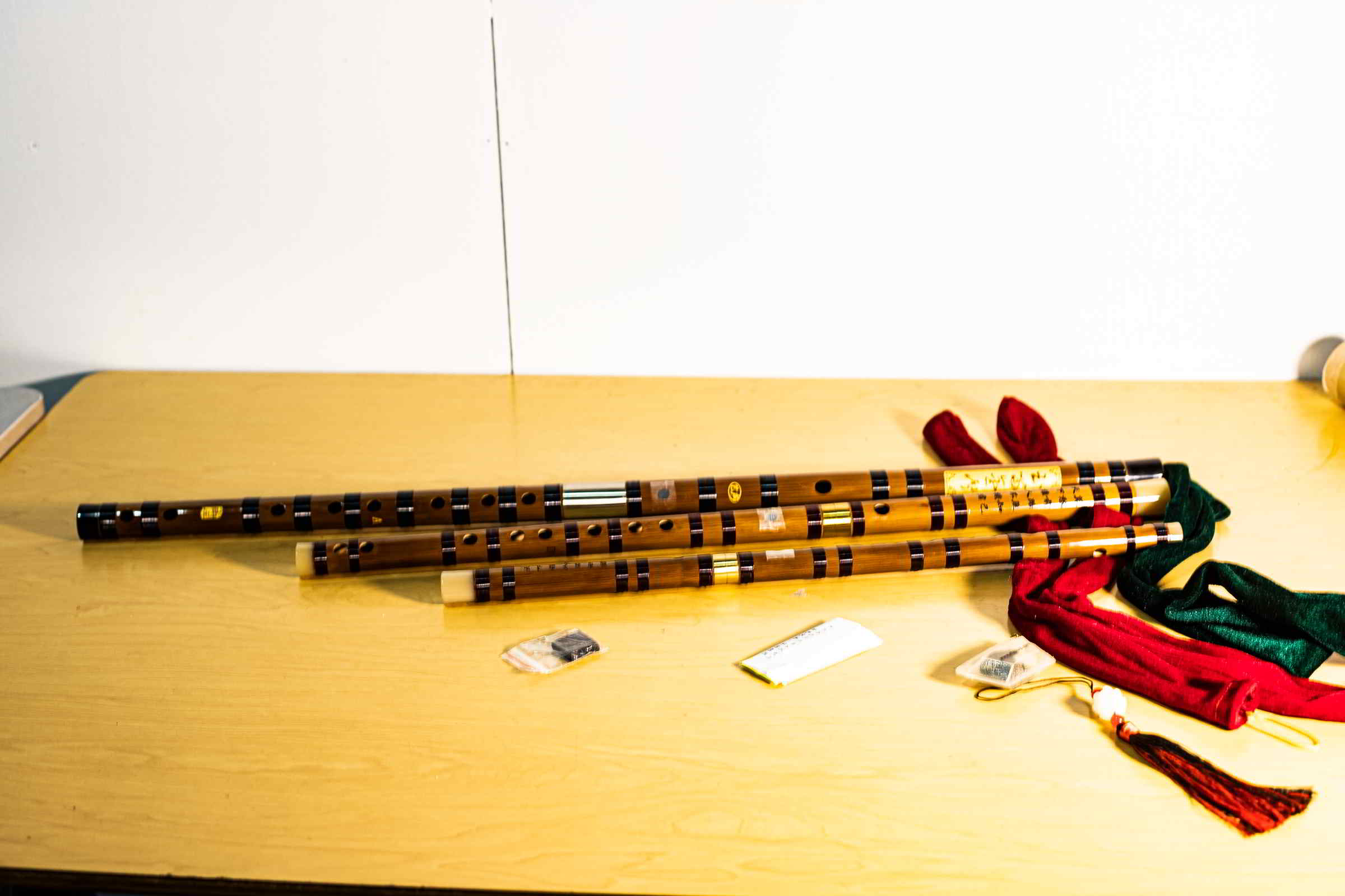 3 bamboo flutes lie on a wooden table.