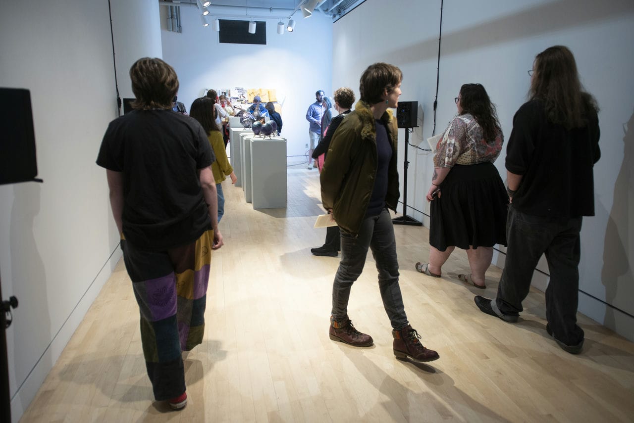 A crowd walks through a gallery space.