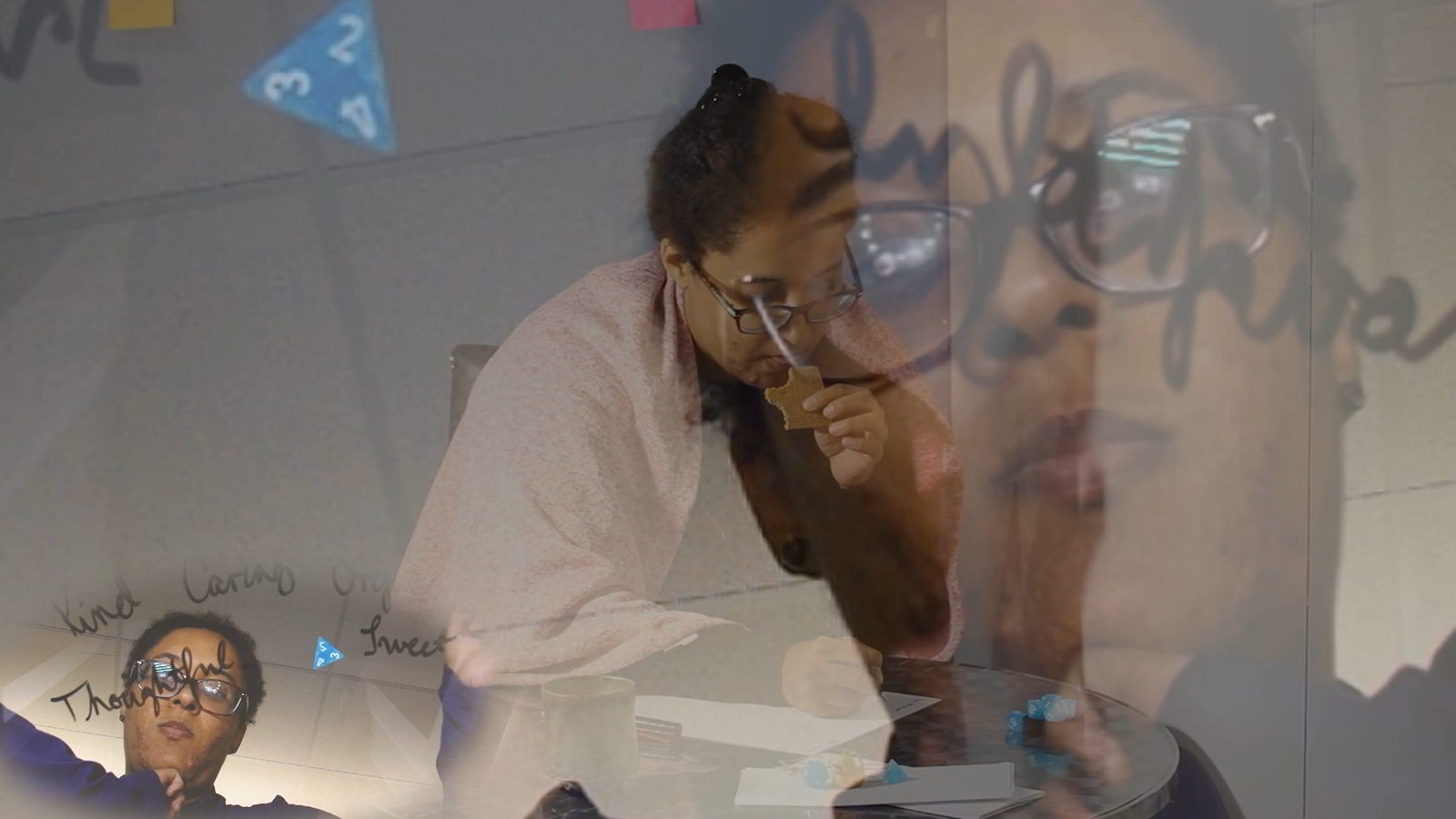 A triangular die in the top left corner, a shot of the artist with words in front of her in the bottom right, a shot of the artist writing while nibbling on a cookie in the mid background, and a closer shot of the artist with words in front of her